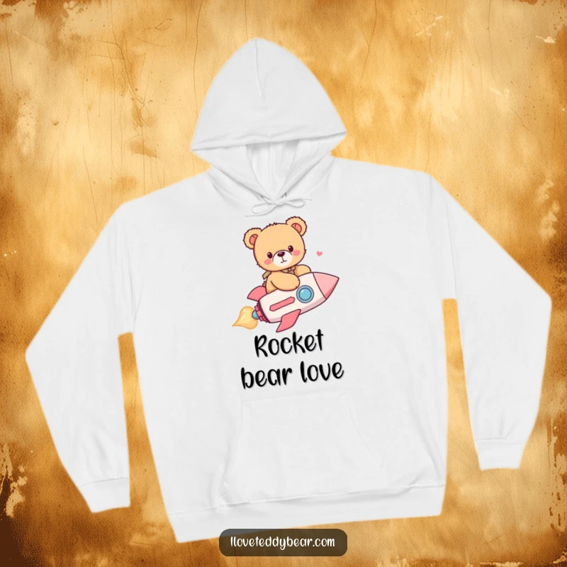 Funny hoodie with a cuddly teddy bear heroically riding a bright red heart-shaped rocket, soaring through a whimsical space.
