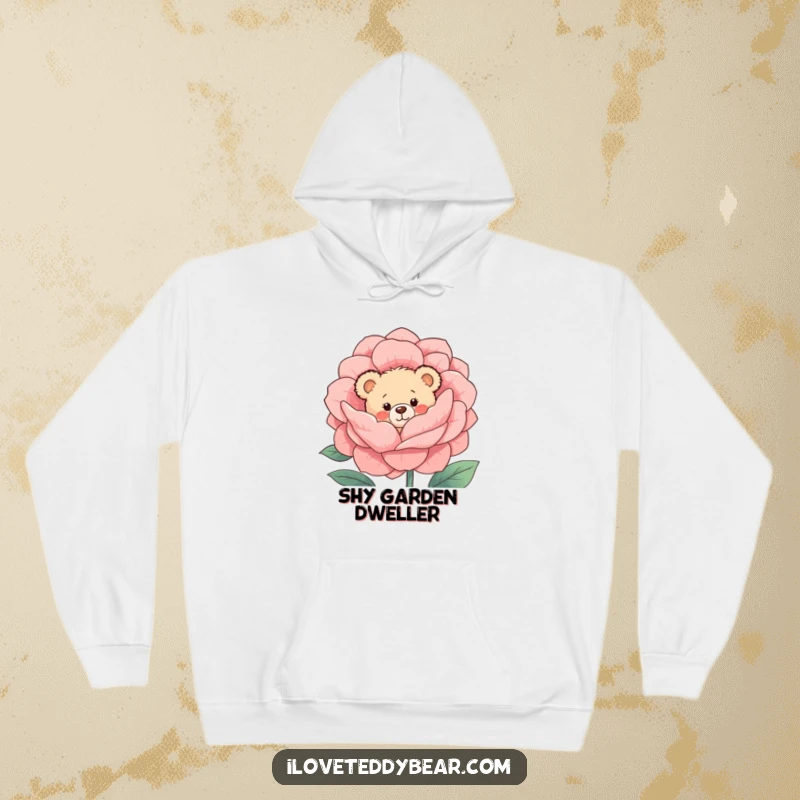 Funny Hoodie: A shy teddy bear with rosy cheeks is peeking from behind a large, beautifully bloomed flower, embodying sweet shyness.
