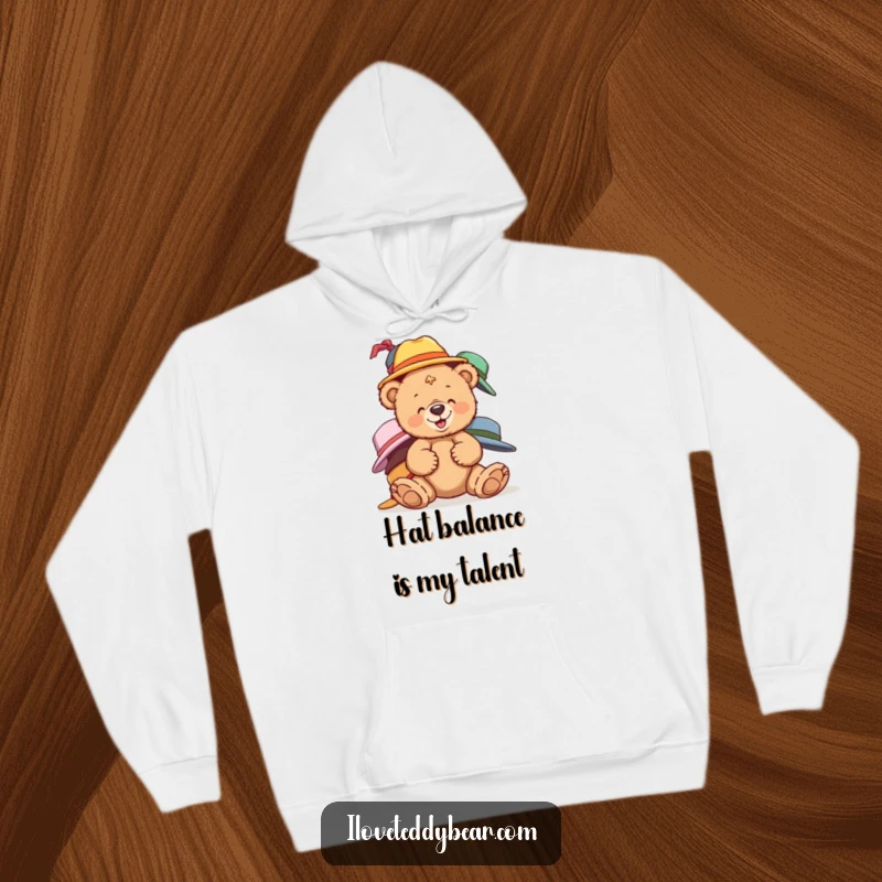 Funny teddy bear hoodie showing a bear giggling while balancing mismatched hats, perfect for cozy humor.