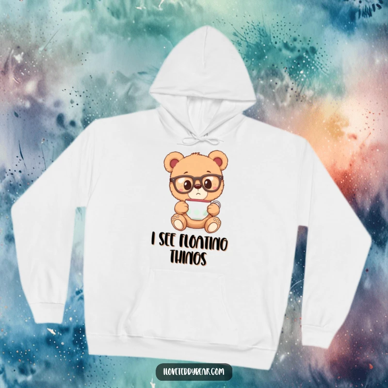 Funny hoodie with a teddy bear in oversized glasses, looking surprised at a floating teacup, offering warmth and whimsical delight.