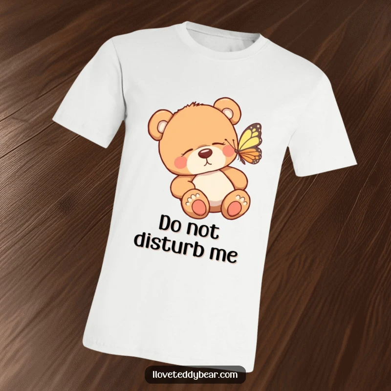 Funny t-shirt showing a drowsy teddy bear being tickled awake by a small, colorful butterfly. A humorous and sweet design.